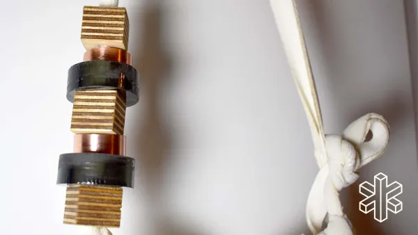 A close-up image of copper pieces and cream-colored string tied in a knot