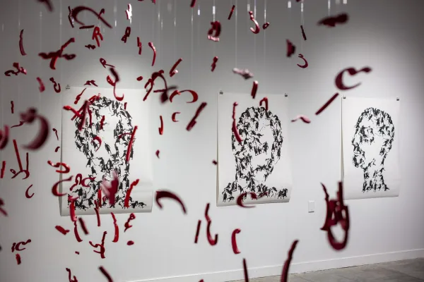 Hanging red letters in Farsi in front of three portraits of people composed of fighting individuals