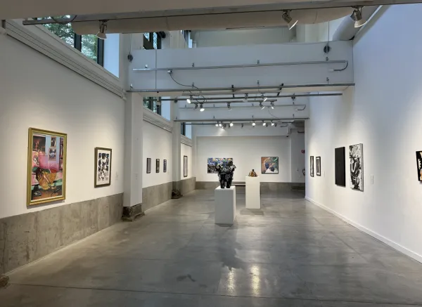 An art gallery featuring two sculptures on pedestals and colorful paintings on the wall