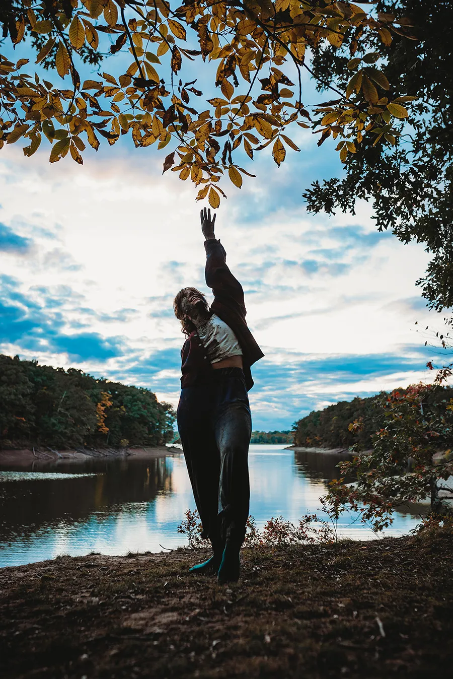 muddy woman at riverbank reaching hand out 
