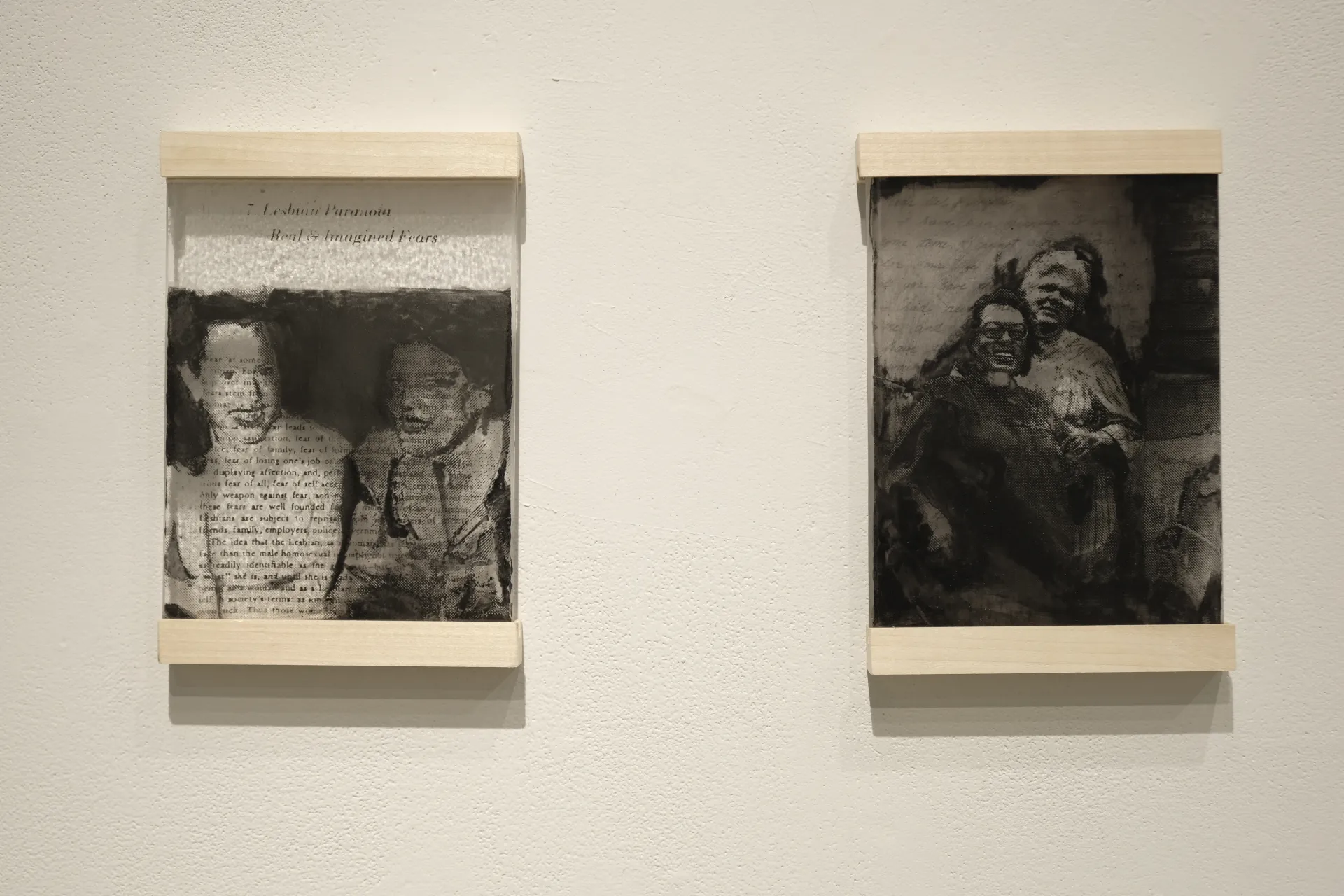 Two glass tiles with black outlines of a lesbian couple. Inside transparent outline written words can be seen.