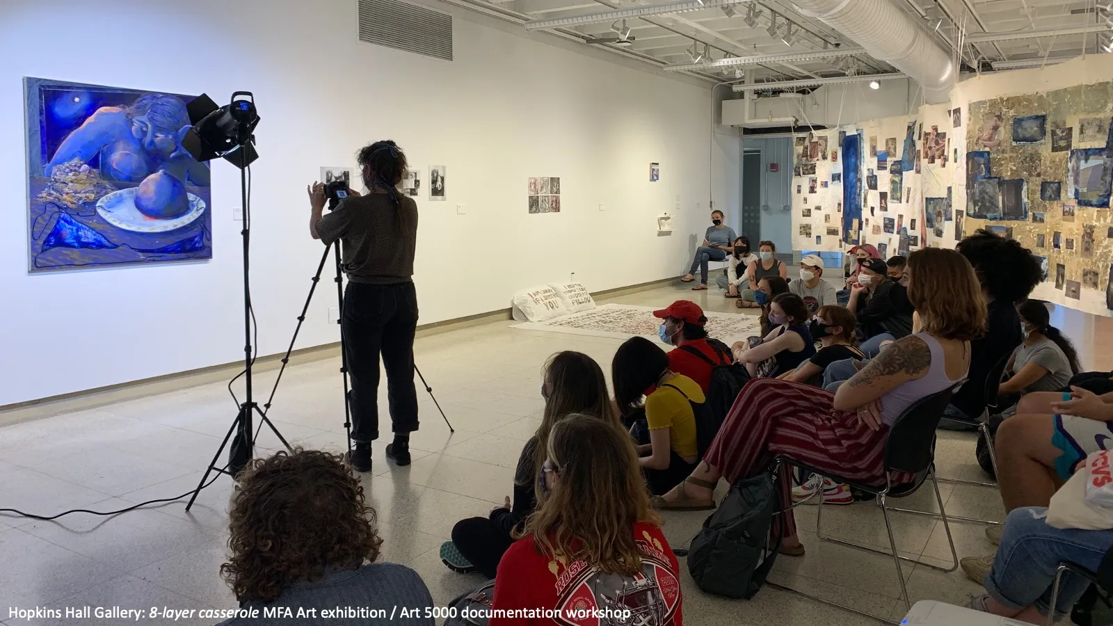 Students look at a painting in the "8-layer casserole" MFA Art exhibition at Hopkins Hall Gallery.