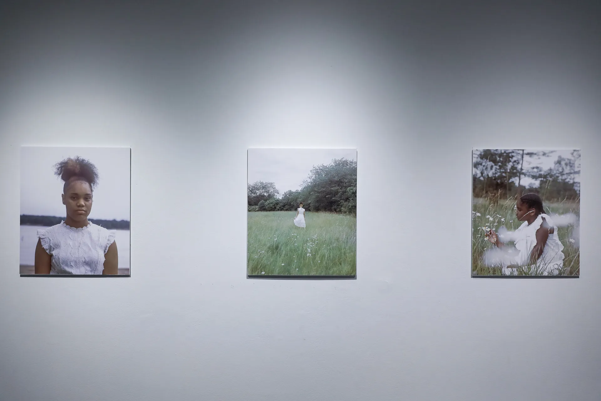 There are three color photos: the one on the left is a portrait of a black girl dressed in white. The middle is a wide shot of a black girl dressed in white standing in a field. The one on the right is a medium shot of a little black girl dressed in white playing with flowers in a field. 