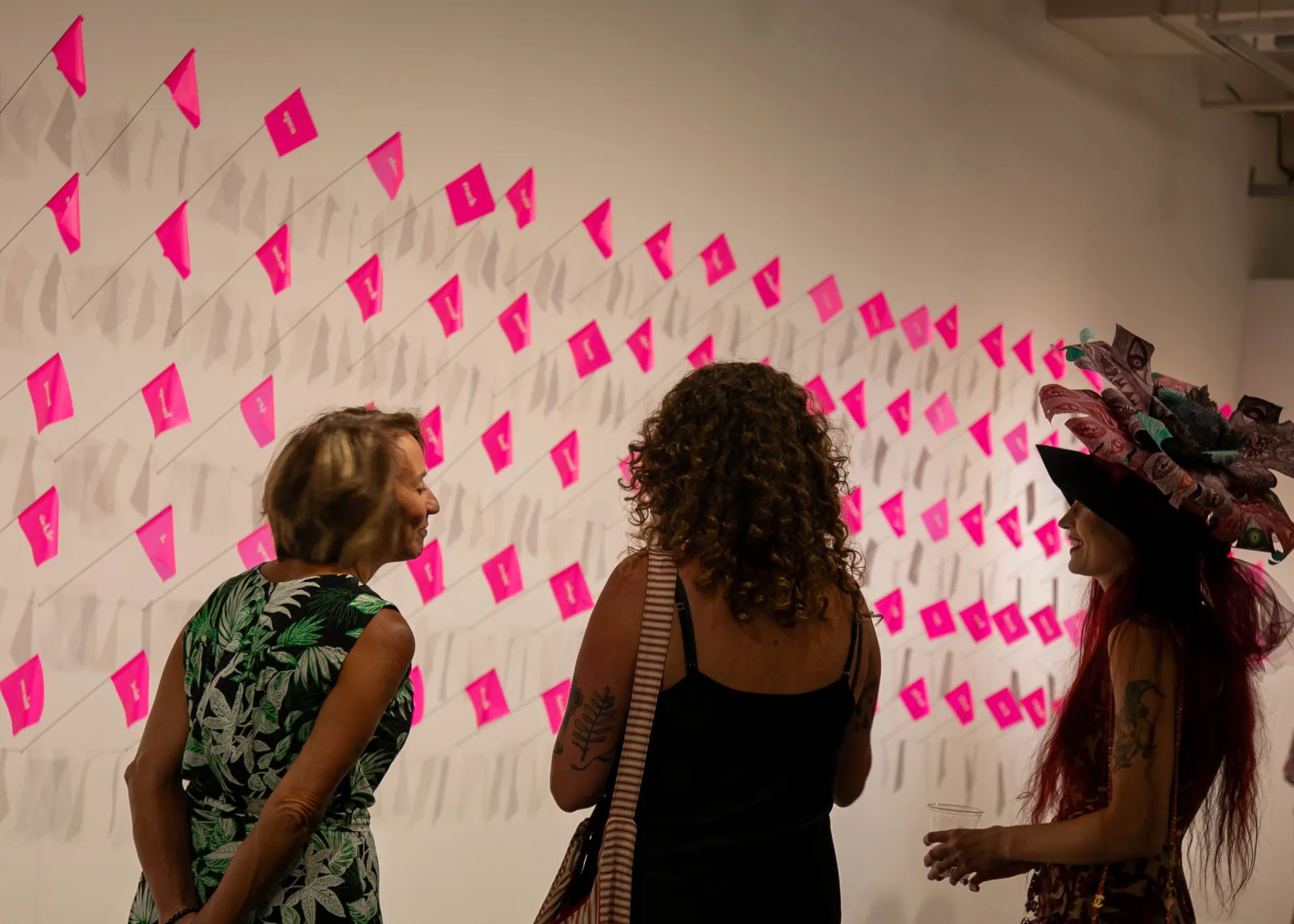 Guests and the artist viewing pink flags on the wall