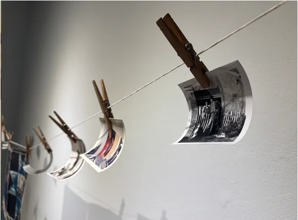 old family photographs hung on a clothesline. The photo in the foreground features a couple and their dog. 