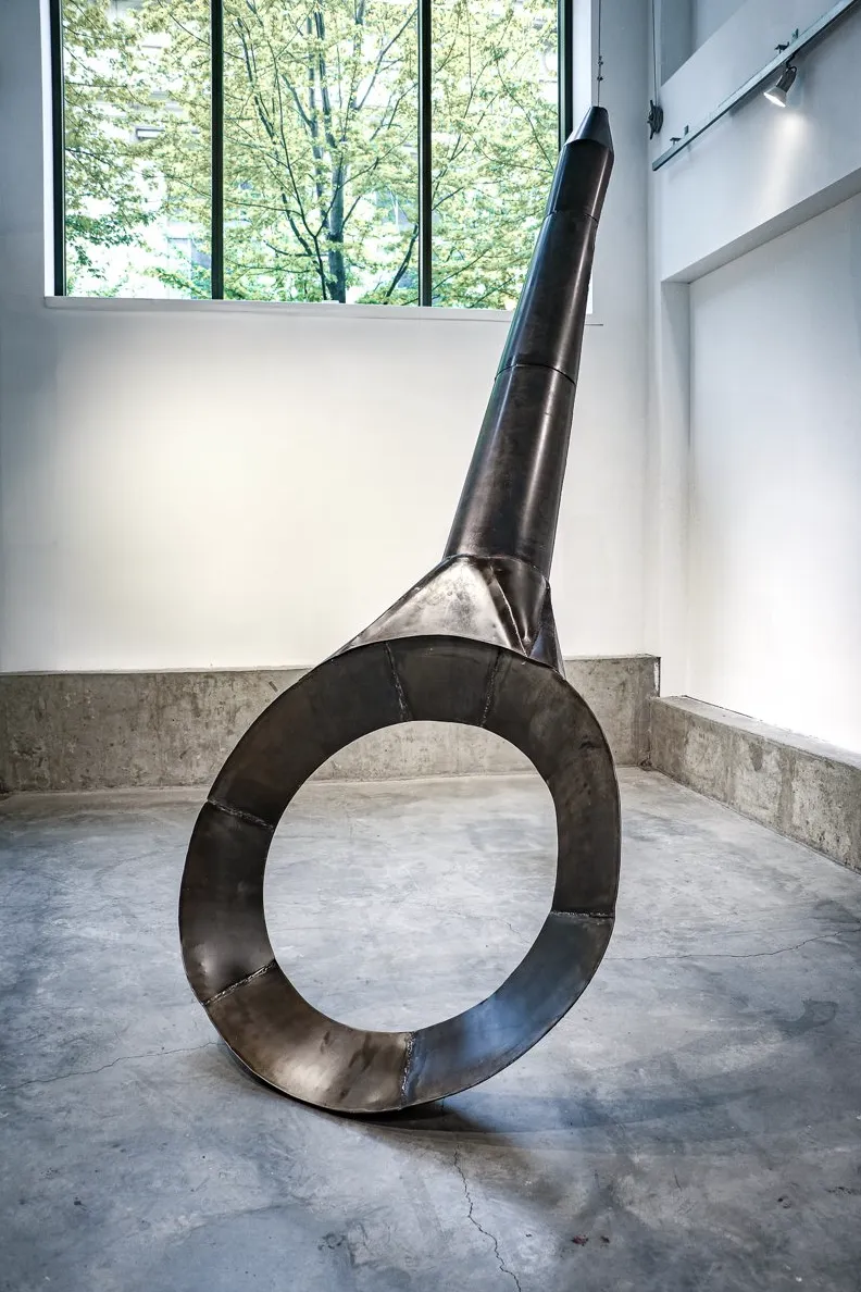 A large metal sculpture shaped like a hollowed cooking pan