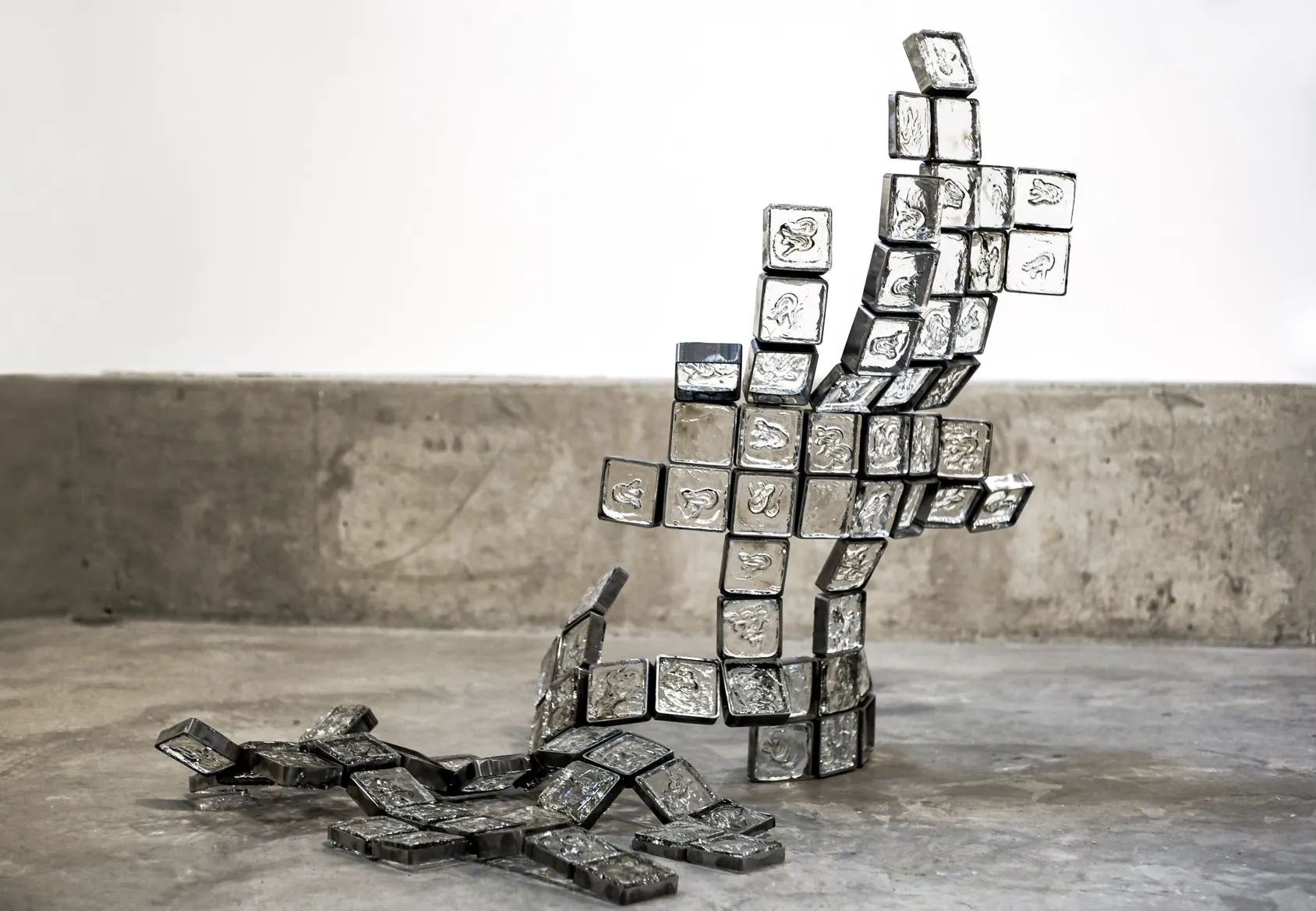 Hot casted glass squares framed with metal to arrange a half standing half fallen sculpture