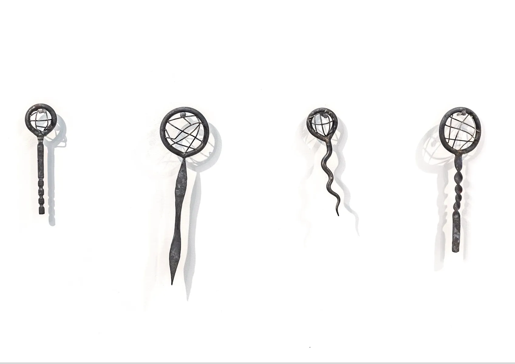 4 Sifters made out of steal hung on a white background