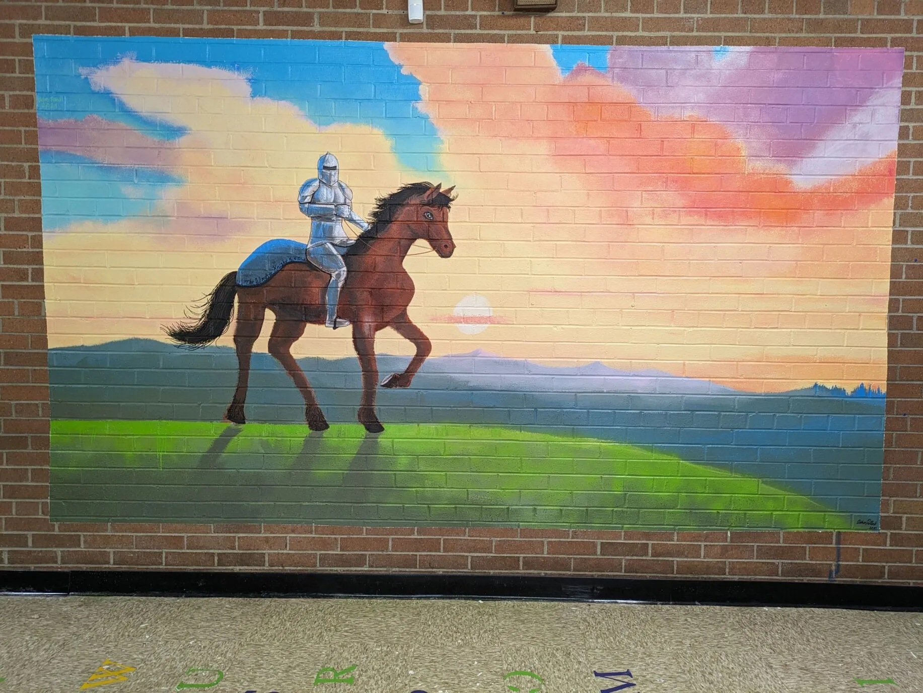 A mural of a knight riding a horse on a hill in front of a sunset backdrop