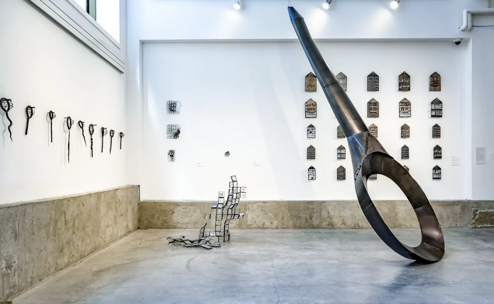 Urban Arts Space with the previous pieces on display, including the giant sifter, glass sculptures, and smaller sifters on the wall