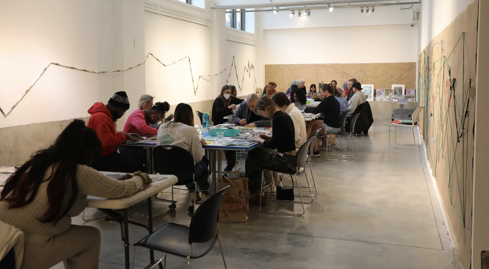 a group of 20 individuals are seated at 4 different tables looking down to their projects
