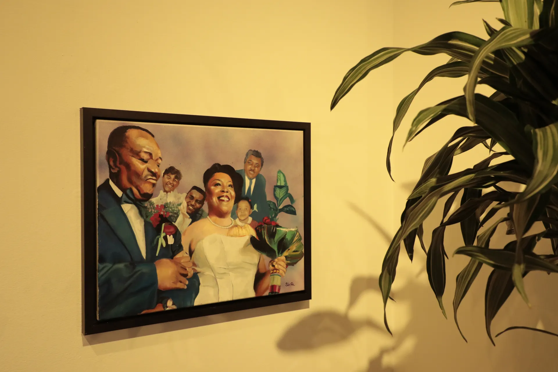 A framed painting on the wall. The painting shows a man in a tux holding the woman's hand who is in a white dress. 