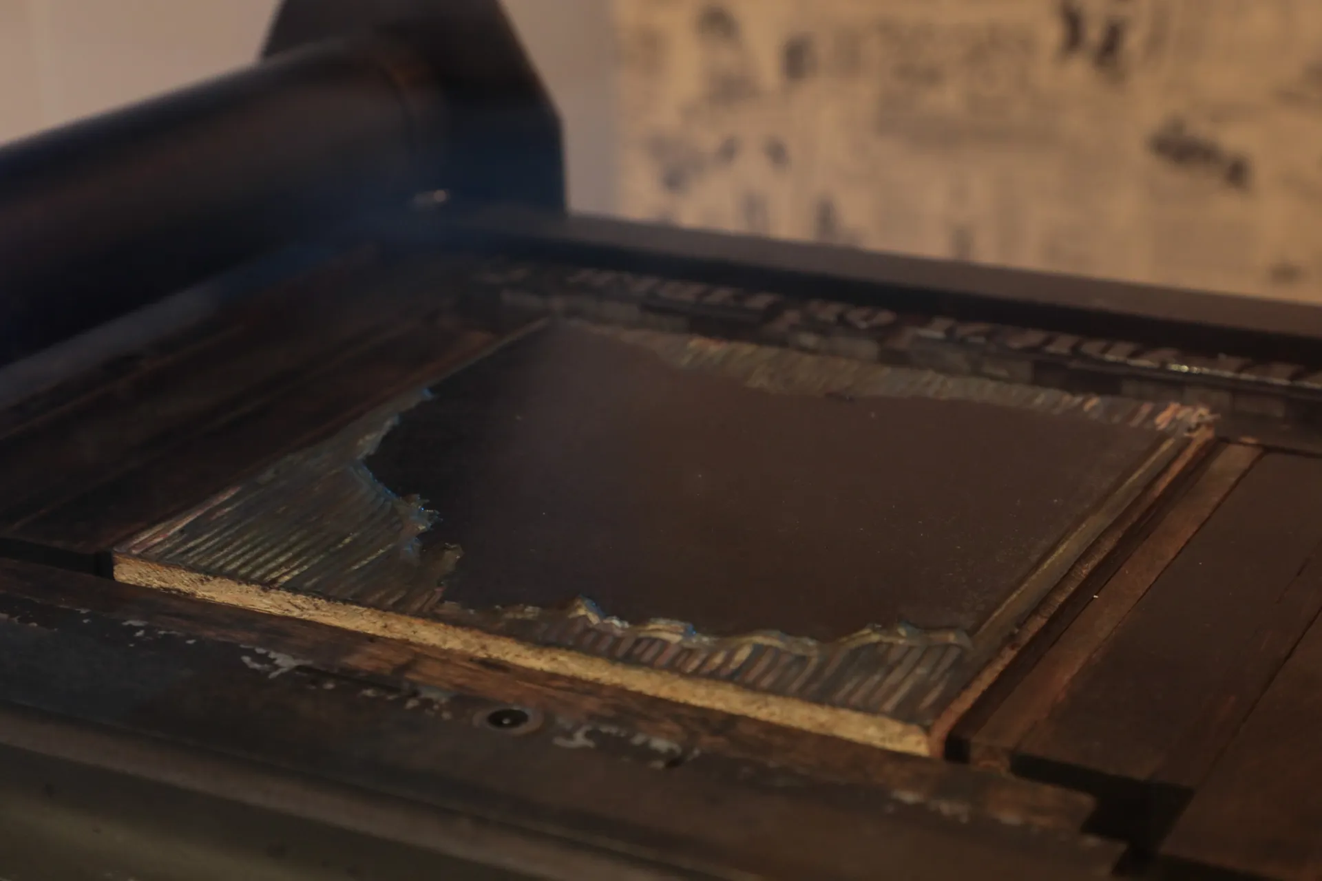 A close up of the printing press with a wooden block shaped like Ohio