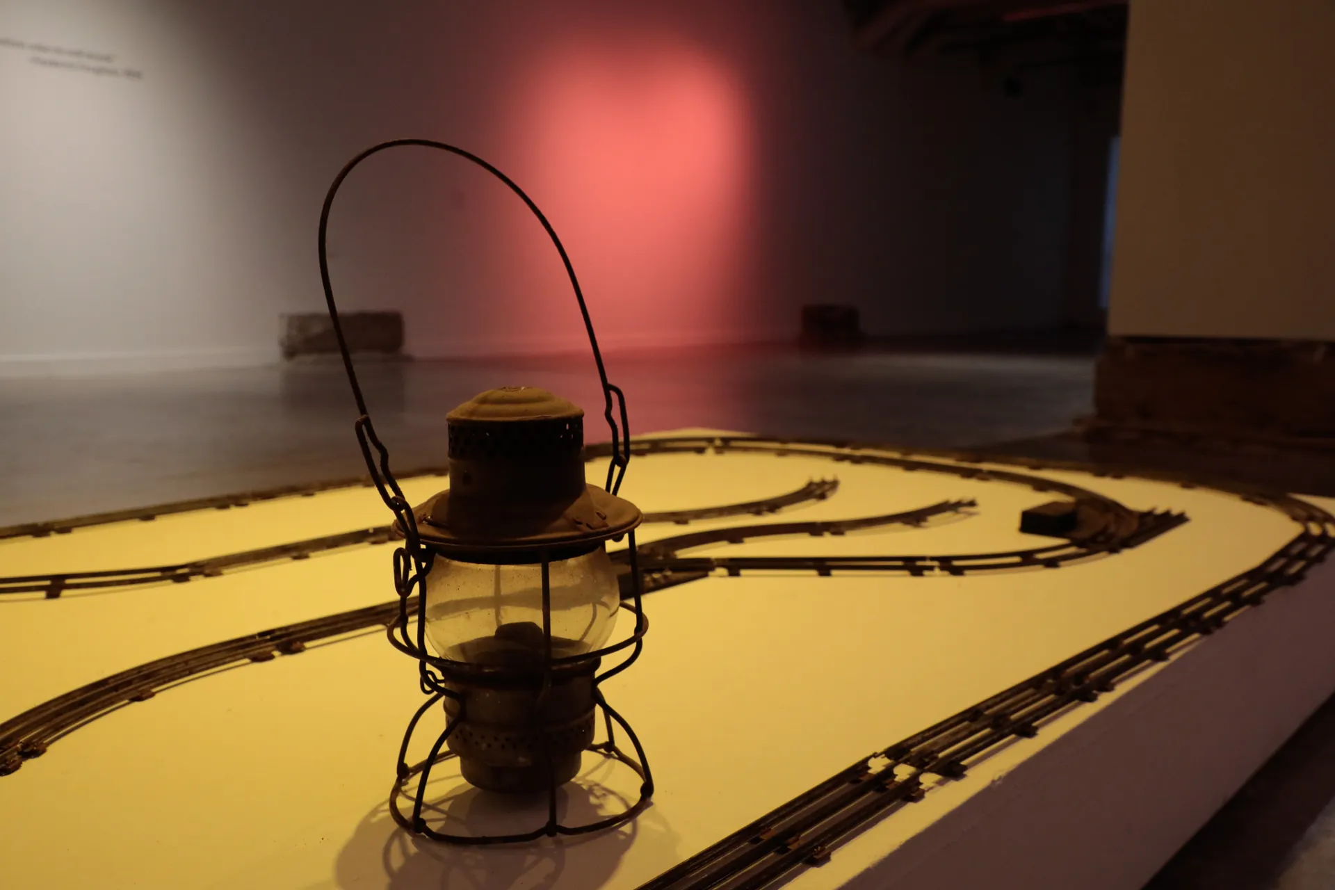 A lantern sits surrounded by tracks with a red light shining in the background