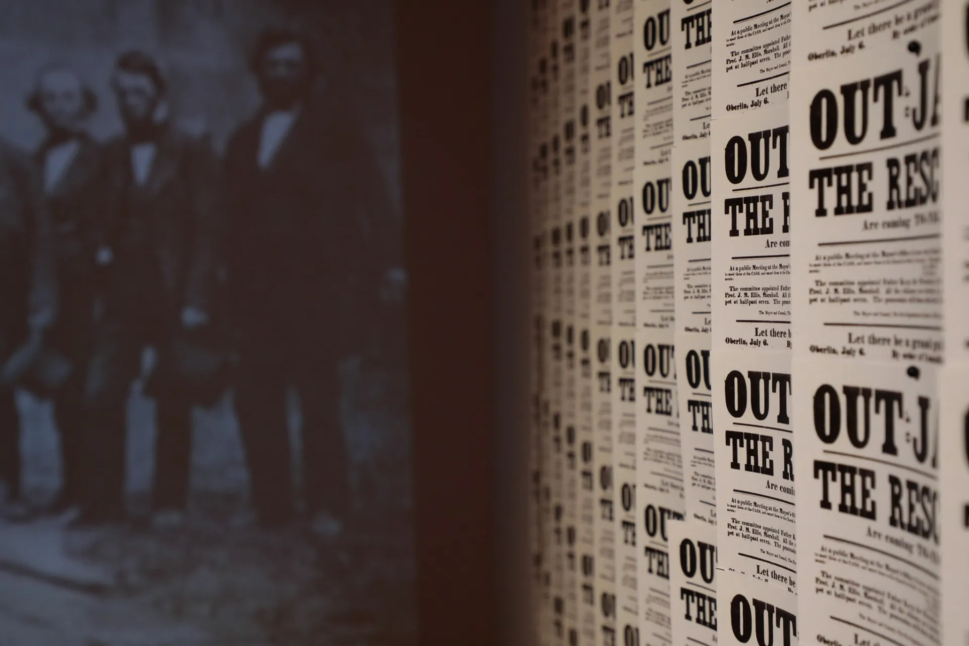 A flyer lines the wall next to a vintage photograph of a group of men 