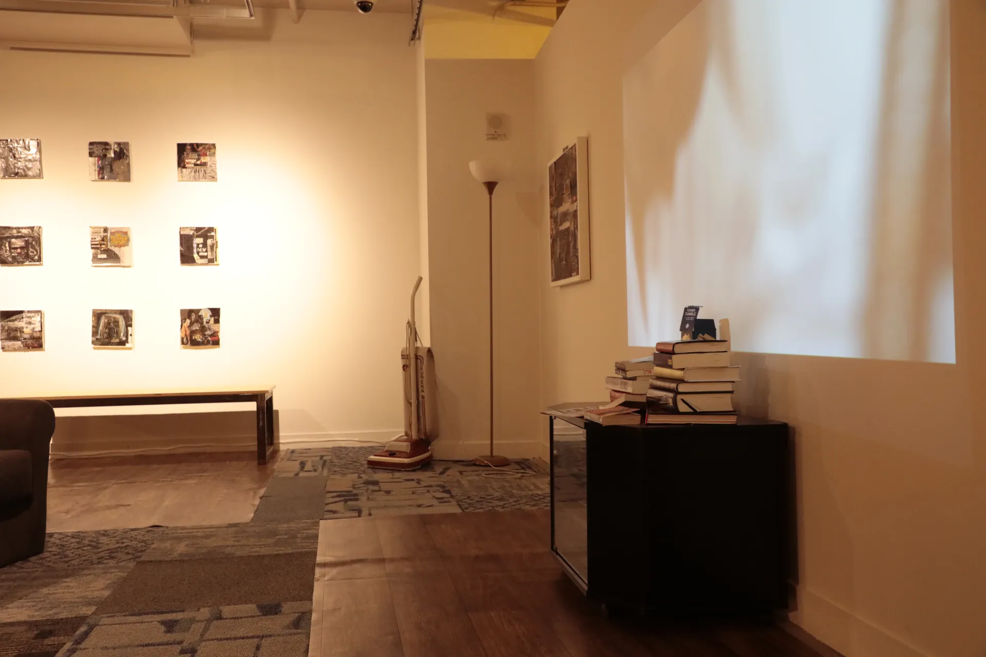 A living room with a lamp and collage art pieces in 3 rows on the wall.