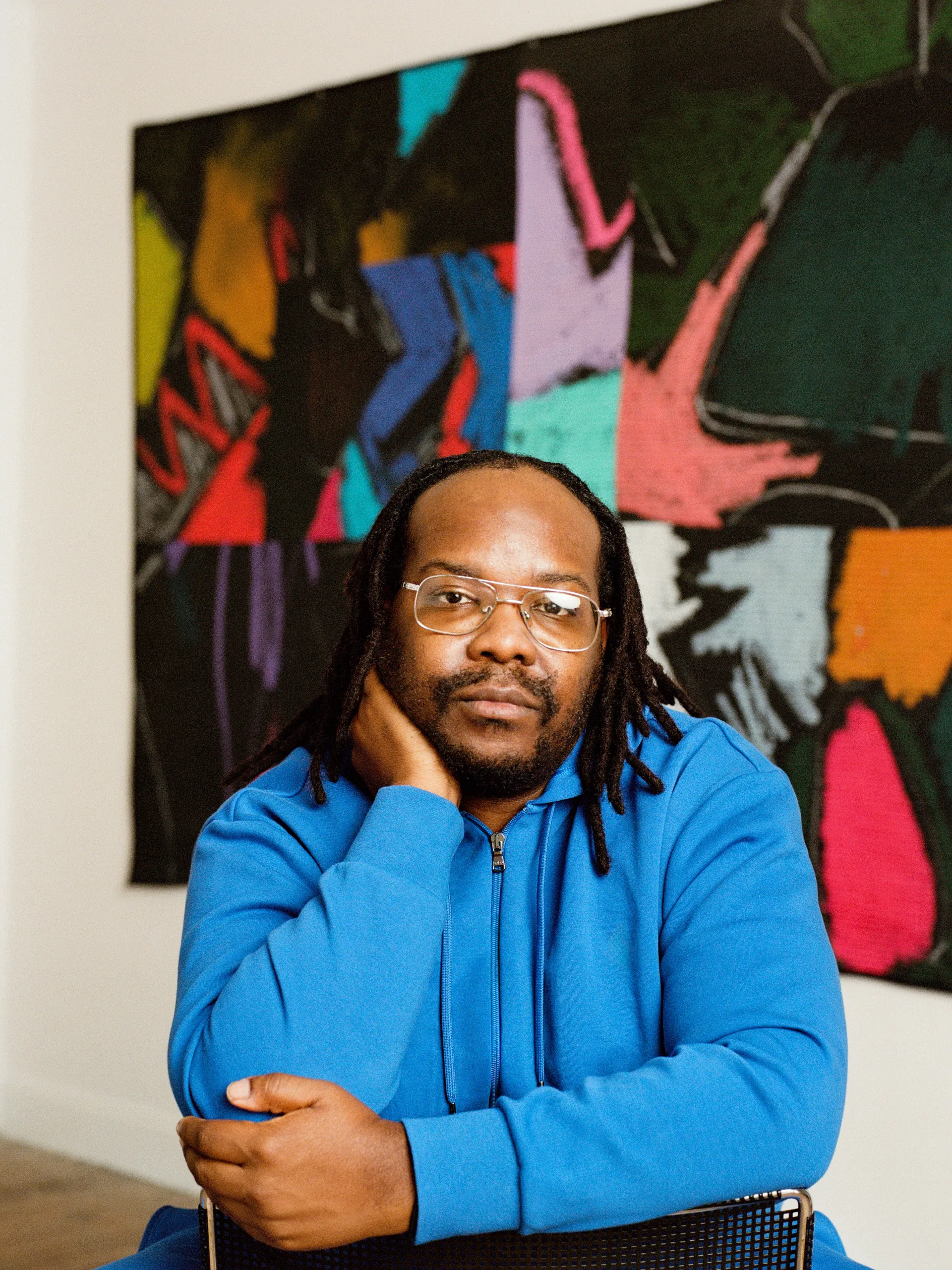 julian jamaal jones in a blue sweater in front of one of his quilts