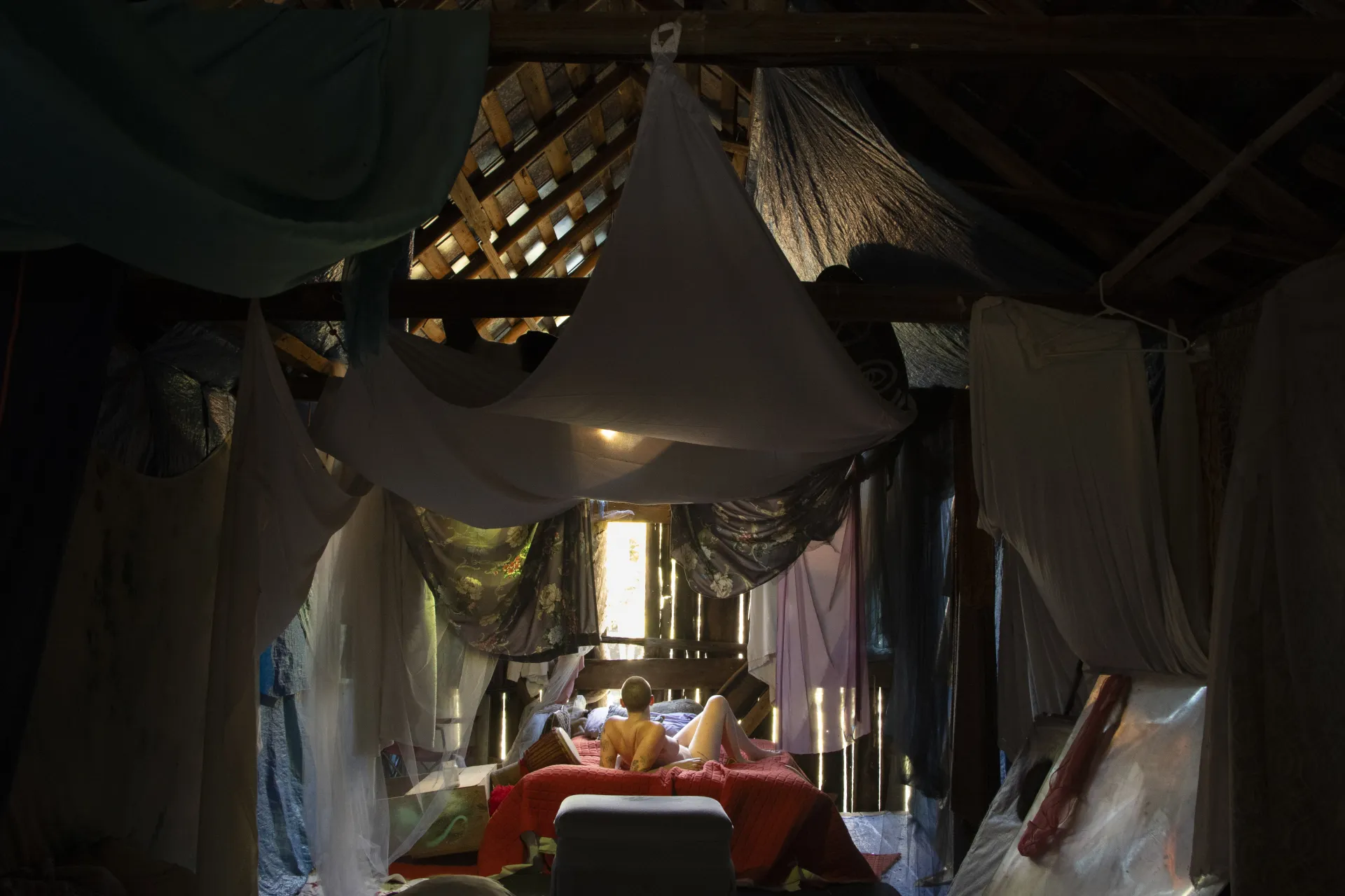 person lying in a bed with cloth draped across the ceiling