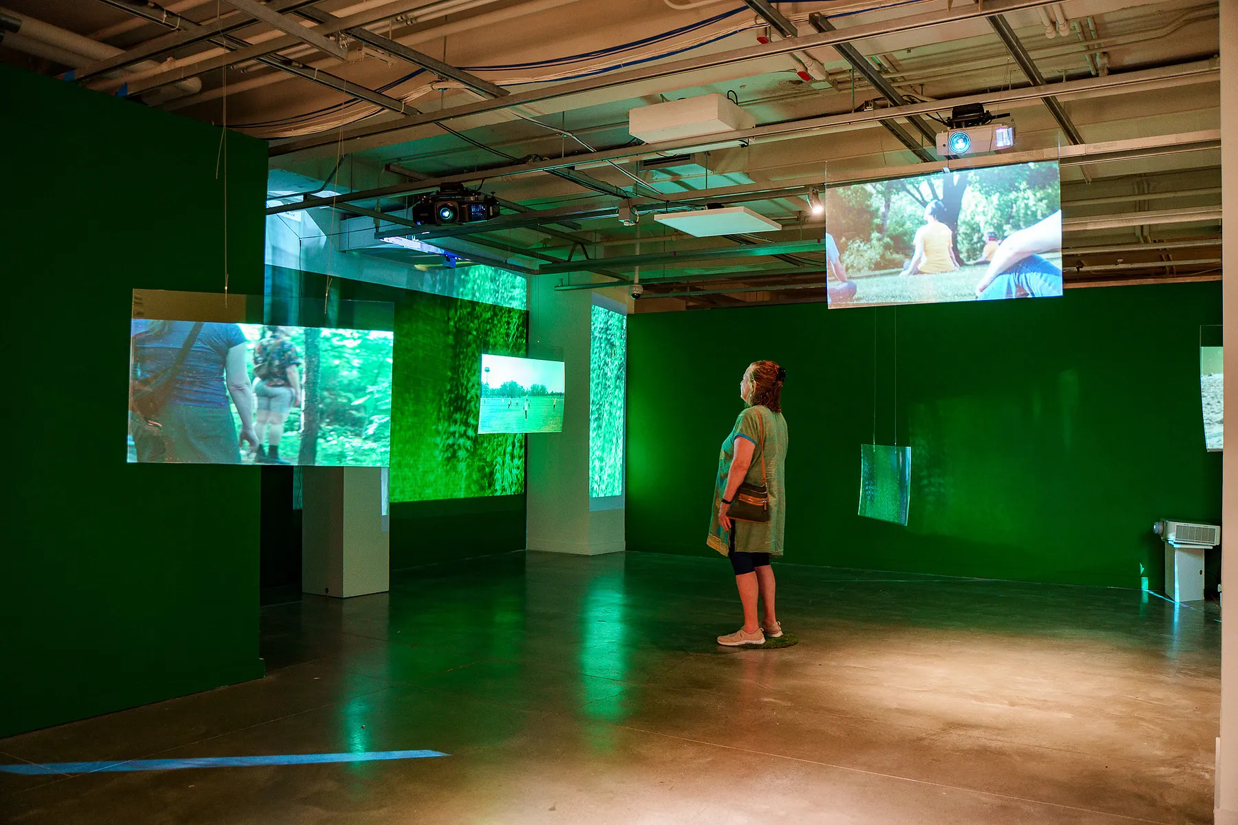 visitor standing in the gallery with screens showing the movement performances at parks