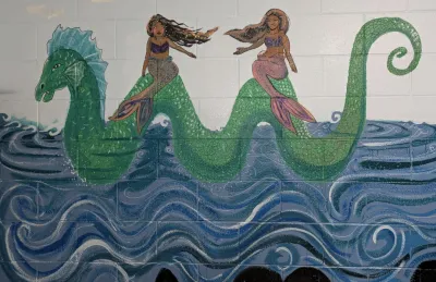 A mural of two mermaids on the back of a sea serpent
