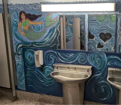A bathroom mural of a mermaid against a blue wall