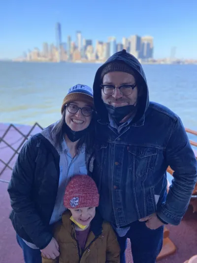 A man, woman, and child smiling for a photo in front of water and city skyline