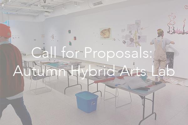 overview shot of two people in a gallery with a folding table between them, text overlay that says "call for proposals: autumn hybrid arts lab"