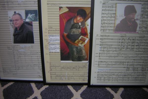 Three framed photos of music sheets with portraits in the middle of each