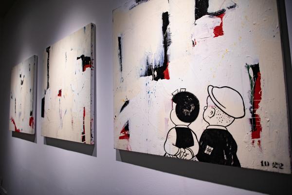 3 paintings with 2 cartoon characters looking at the canvases 