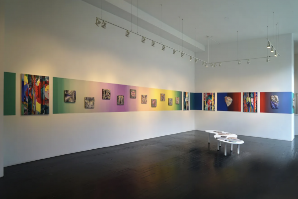 Art gallery with many colorful works hanging closely to one another 