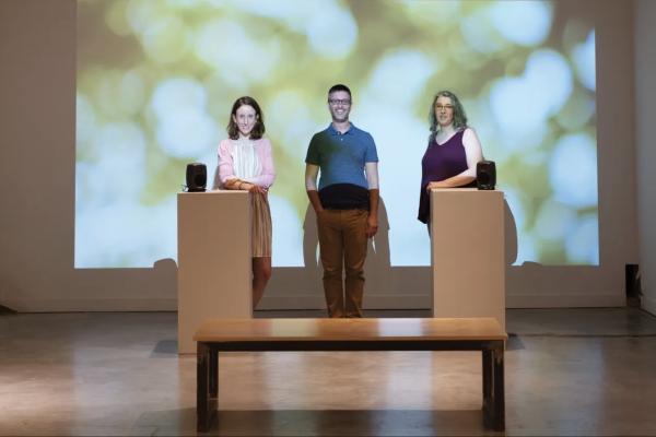 Three people standing in front of a green projected image