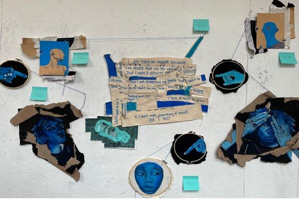Collage of painted faces and words on cardboard