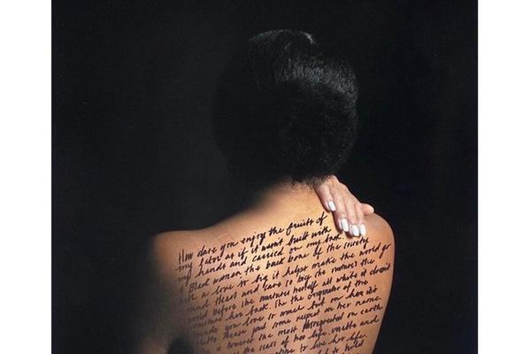 Photo of a dark-haired woman with her bare back to the camera and a hand over her shoulder, words written across her back