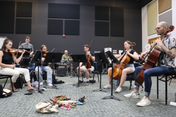 A photo of 7 musicians playing classical instruments in a practice room.