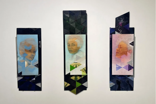 A photo of three portraits painted in light colors, primarily blue, green, and purple, hanging on the wall.