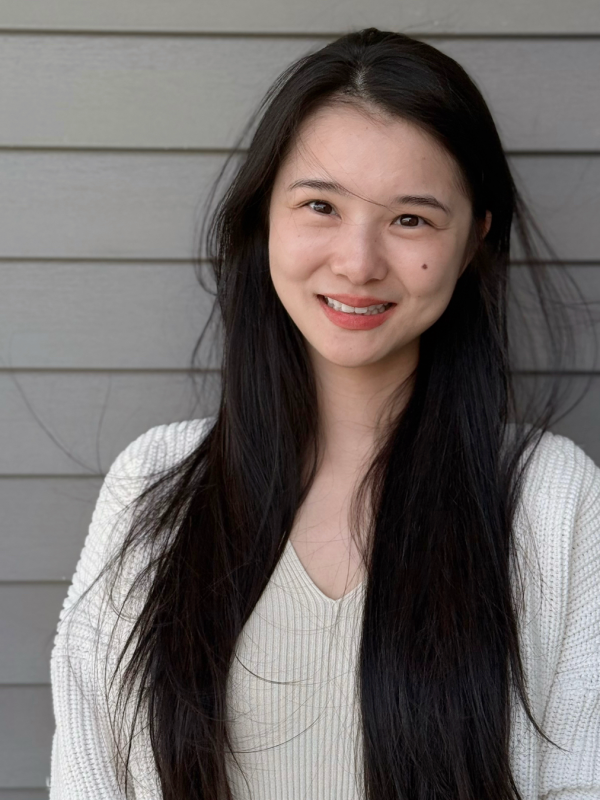 Xiaoxiao smilling with long black hair and a white sweater