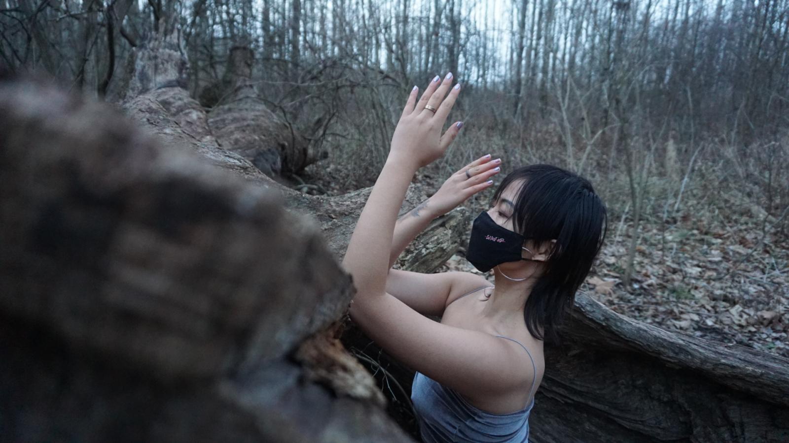 girl wearing a mask while dancing in the middle of the woods