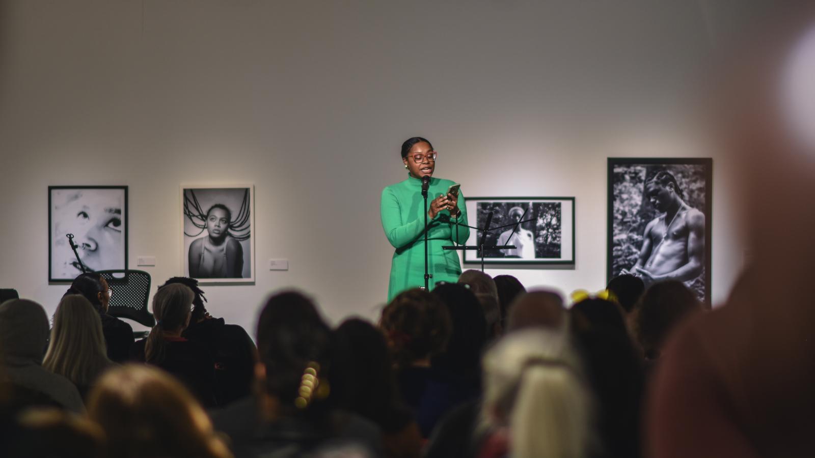 Ajanae in a green dress reading for a crowd