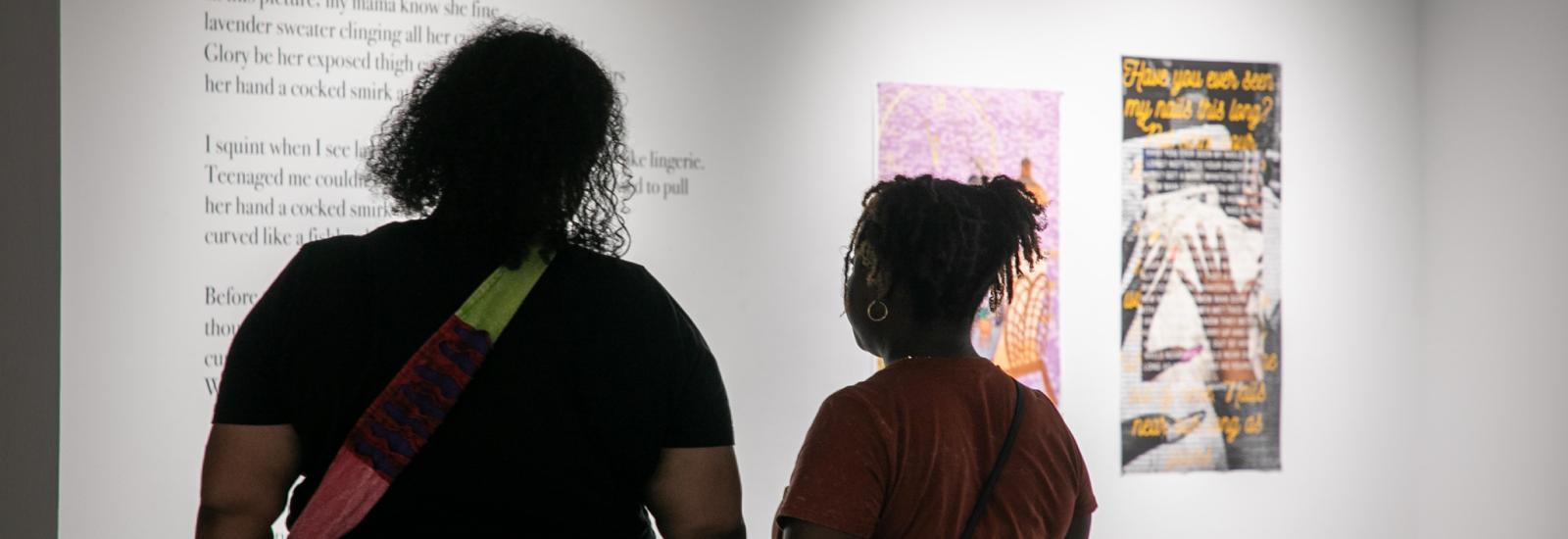 Two women looking at poetry and artwork.