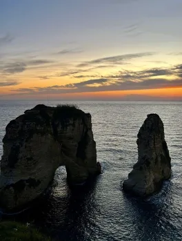 Two rocks perched out of the sea in the foreground in front of a sunset